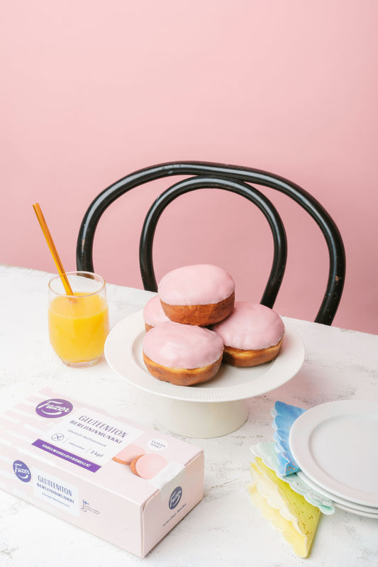 Glutenfria munkar med rosa glasyr i frukoststillleben