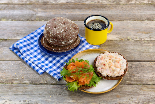 Glutenfritt mörkt portionsbröd Reissumies halverat med pålägg och kaffe på blårutig duk